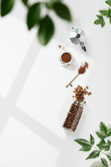 Coffee composition on light grey background, window shadow and green branches, flat lay, top view