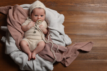 Canvas Print - Cute newborn baby with pacifier on wooden background, top view. Space for text