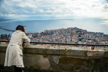 Wall Mural - woman lay over a balcony from the castle overlooking the Napoli