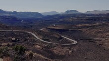 A Tilt Establishing Shot Of Vehicles Navigating The Tight Winding Valley Road Through The Golden Gate National Park, The Surrounding Grasslands Burnt From A Recent Veld Fire, Free State, South Africa