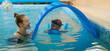 © ninelutsk - Toddler child learning to swim in indoor swimming pool with teacher. Floating in the water, balancing and general physical activity for kids, early development. Boy kid trained to kick legs and float