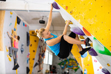 Caucasian Woman Exercising On Wall In Climbing Gym During Bouldering Training.