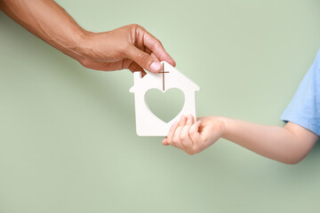 Hands of family with figure of church on green background. Concept of Christianity