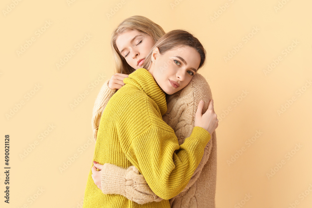 Portrait of hugging young sisters on color background