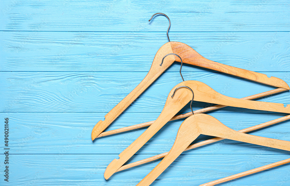 Clothes hangers on color wooden background