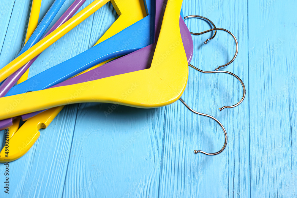 Bright clothes hangers on color wooden background