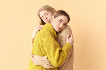 Canvas Print - Portrait of hugging young sisters on color background