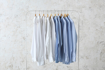 Rack with clean white and blue shirts on grunge background