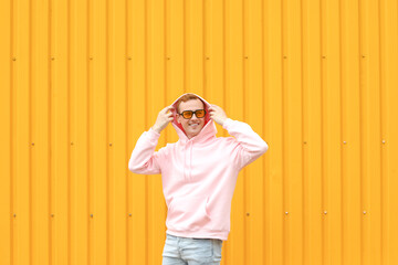 Wall Mural - Young guy in stylish hoodie on color background