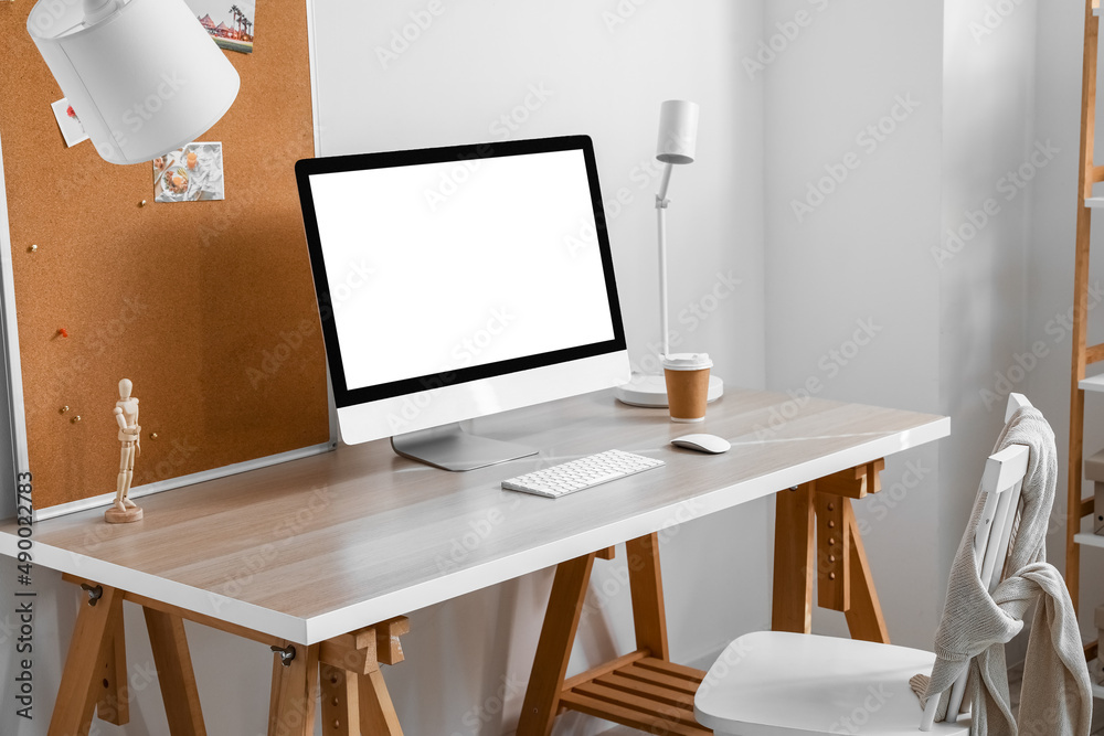 Interior of light office with modern workplace, computer and lamp