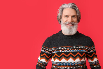 Canvas Print - Handsome senior man in knitted sweater on red background