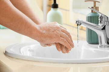 Man washing his hands with soap in ceramic sink, closeup