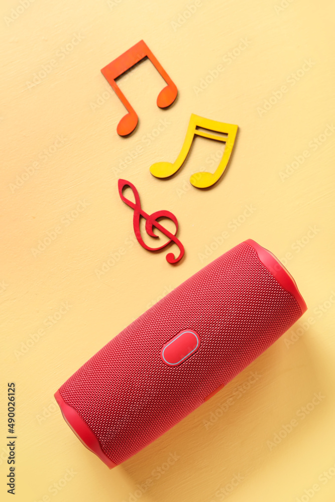 Wireless portable speaker and music notes on color background