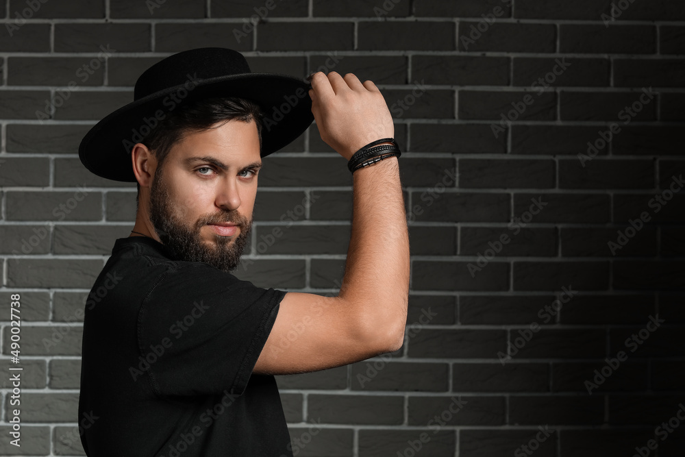 Stylish bearded man on dark brick background