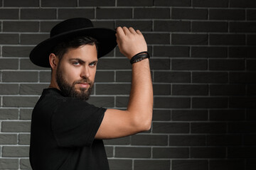 Wall Mural - Stylish bearded man on dark brick background