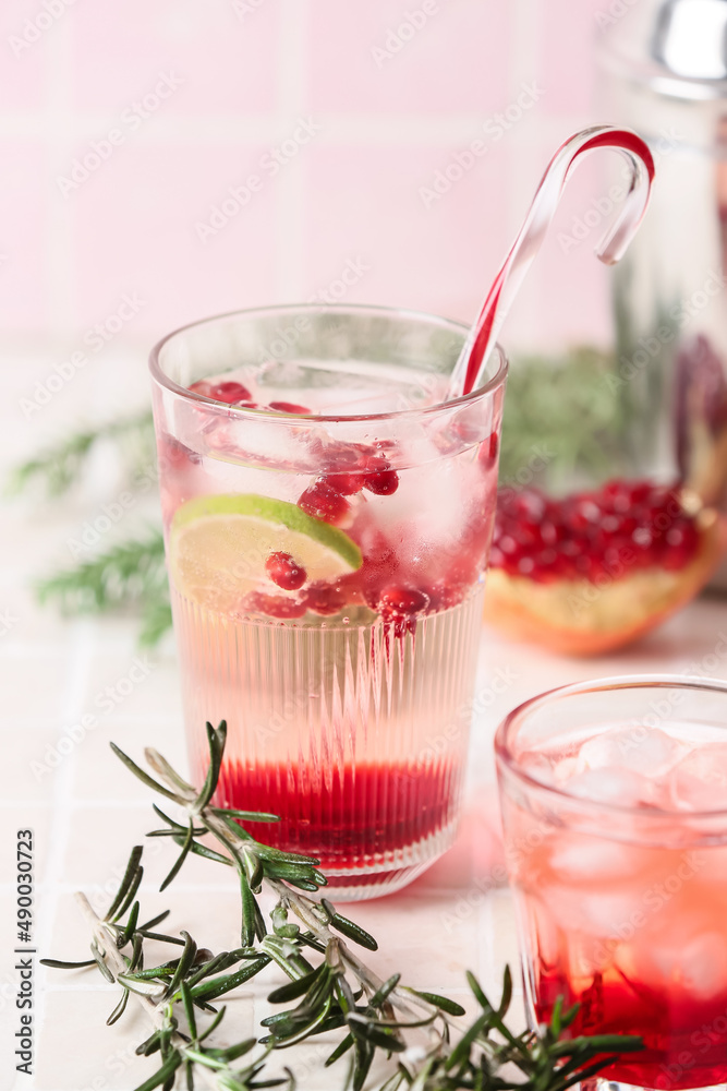 Glasses of tasty pomegranate cocktail on tile background
