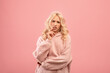 © Prostock-studio - Pensive young lady thinking about question, touching lips and looking at camera, standing over pink background