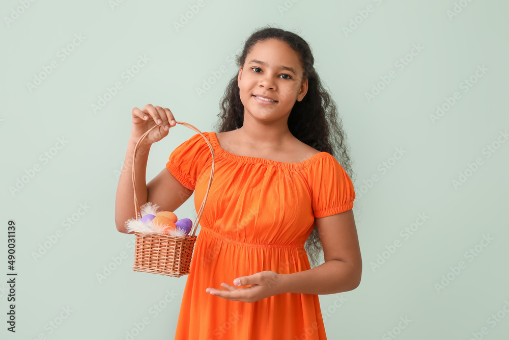 Cute African-American girl with Easter basket on color background