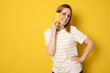 © Danko - Portrait of a beautiful young casual woman talking on smartphone isolated over yellow background