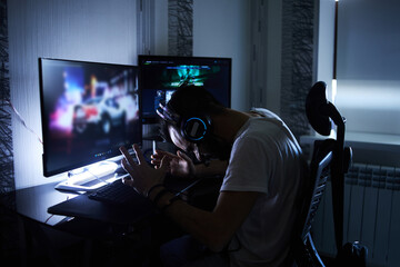 a young 30-year-old gamer is sitting at a computer, playing computer games, nervous, angry, worried.selective focus with low depth of focus