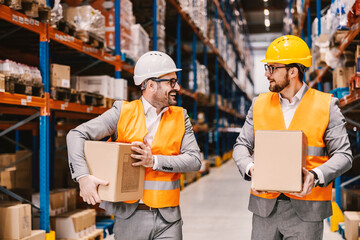 Two supervisors taking boxes with goods on quality control at warehouse.