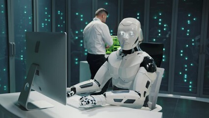 Cybernetic white robot using desktop computer programming software working with people in server room. Data center. Artificial intelligence.