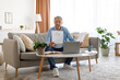 © Prostock-studio - Man holding paper reading report working on laptop at home