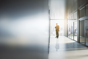 Aufkleber - Thoughtful young businessman looking out of window in abstract bright light office interior with mock up place on silver wall. Success, future and tomorrow concept.