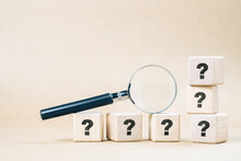 Magnifying Glass On Wood Cubes With Many Question Marks, Confusing, Frequently Asked Questions, And Doing Test Concept