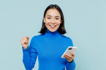 fun young woman of asian ethnicity 20s years old wear blue shirt hold in hand use mobile cell phone 