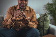 © Dragana Gordic - A modern African man sits at a table in the living room and takes blood from his finger due to diabetes. Everyday life of a man of African American nationality