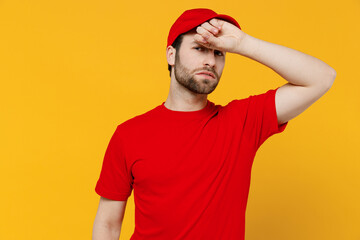 Wall Mural - Professional sick ill sad delivery guy employee man in red cap T-shirt uniform workwear work as dealer courier put hand on forehead isolated on plain yellow background studio portrait Service concept