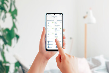 Aufkleber - Control home devices with smart home app. Smart phone in hands, living room interior in background. Modern home automation app interface