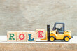Toy forklift hold letter block e to complete word role on wood background
