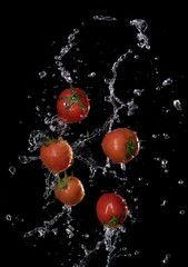 Wall Mural - fresh red tomatoes in splash of water isolated on black background