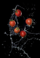 Wall Mural - fresh red tomatoes in splash of water isolated on black background