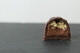 Fototapeta Big Ben - incision chocolate case candy stuffed with chocolate pralines and crushed peanuts close-up on a gray background with space for copyspace text. Chocolate Day Sweet Homemade Desserts