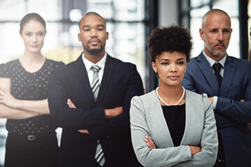 Driven by the executive dream. Shot of a focused businesswoman standing in front of her team at work.