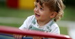 © Marco - Carefree little boy spinning at playground carousel close-up face smiling