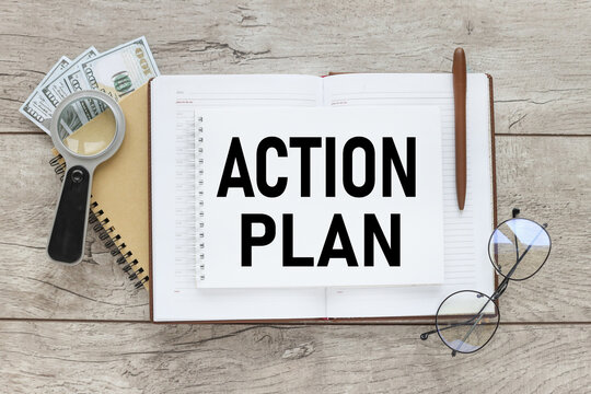 wooden background with open notepad with text. Action Plan