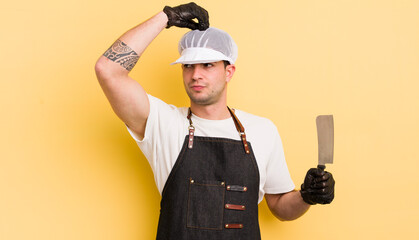 Wall Mural - young handsome man smiling happily and daydreaming or doubting. butcher concept