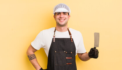 Wall Mural - young handsome man smiling happily with a hand on hip and confident. butcher concept