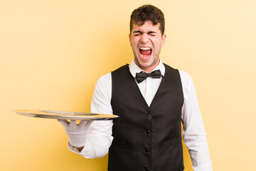 Wall Mural - young handsome man shouting aggressively, looking very angry. waiter and tray concept