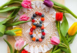 A composition of tulip flowers and the number 8 for the holiday of the eighth of March. The number 8 is laid out from miniature fruits made of polymer clay on a lace napkin. international women's day