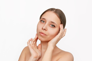 Wall Mural - Portrait of a young beautiful caucasian woman with makeup touching the skin of her face isolated on a white background. Beauty and fashion. Skin care