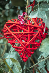 Wall Mural - Vertical shot of the beautiful red decorative wooden heart on a tree branch on a blurred background