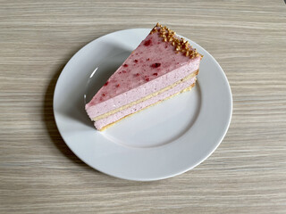 Poster - A piece of delicious strawberry cake on a white plate on a wooden table