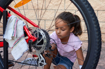 Canvas Print - Photo of a young girl fixing a bicycle wheel March 8 - International Day of Working Women