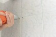 © elabracho - man drills with an electric drill into the wall of tiles in the bathroom