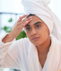 Should I be worried about wrinkles too. Shot of a young woman looking at her face in a bathroom mirror at home.